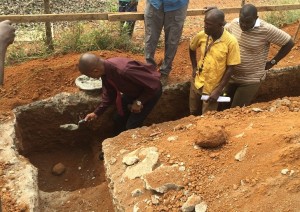 The third hole, Pastor John Moiba, Executive Secretary of the Sierra Leone Mission, starts us out by placing the first dollop of cement on the cornerstone of the phyiso building.